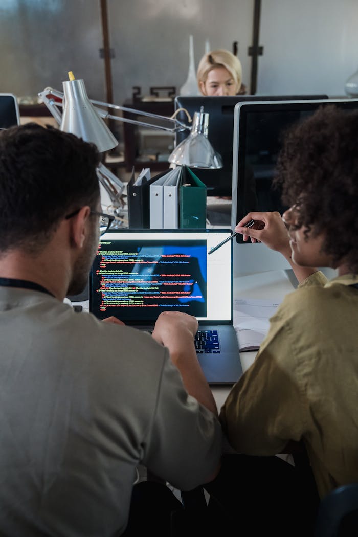 about-01 Two developers engage in software programming on a laptop in a modern office setting.